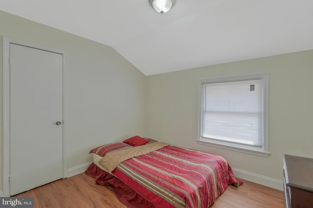 bedroom with baseboards, lofted ceiling, and wood finished floors