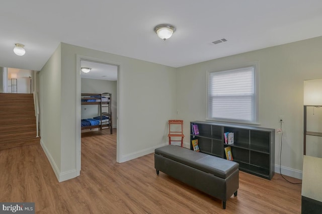 living area featuring visible vents, baseboards, wood finished floors, and stairs