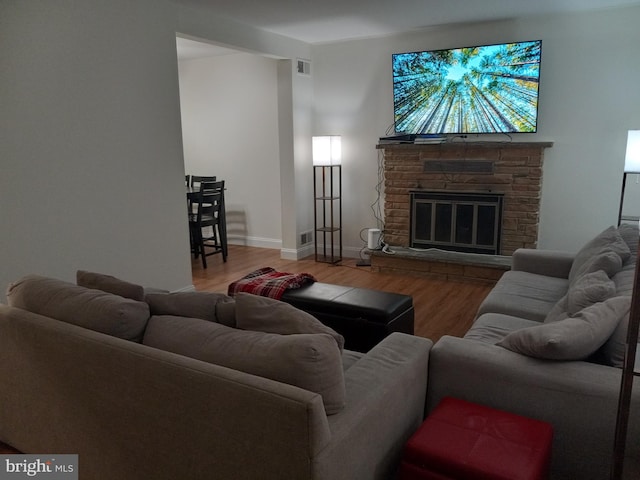 living area with visible vents, a fireplace, baseboards, and wood finished floors