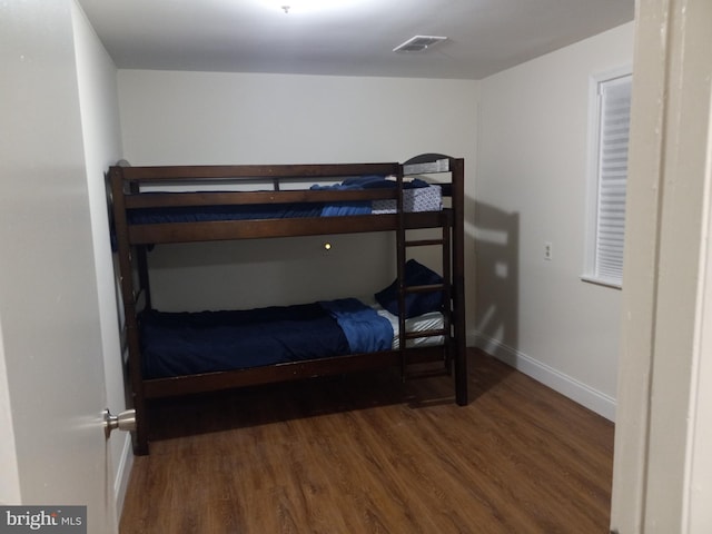 bedroom with wood finished floors, visible vents, and baseboards