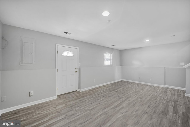 foyer with visible vents, wood finished floors, electric panel, and baseboards