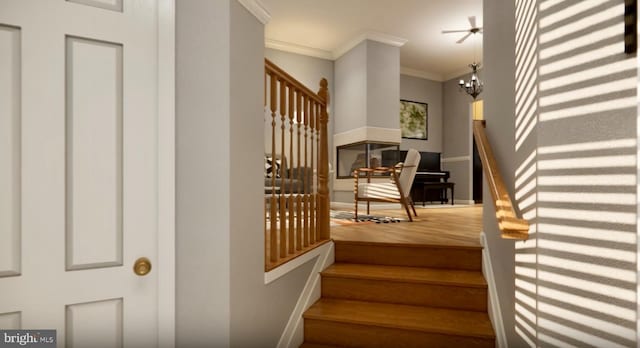 stairs with an inviting chandelier, crown molding, and wood finished floors