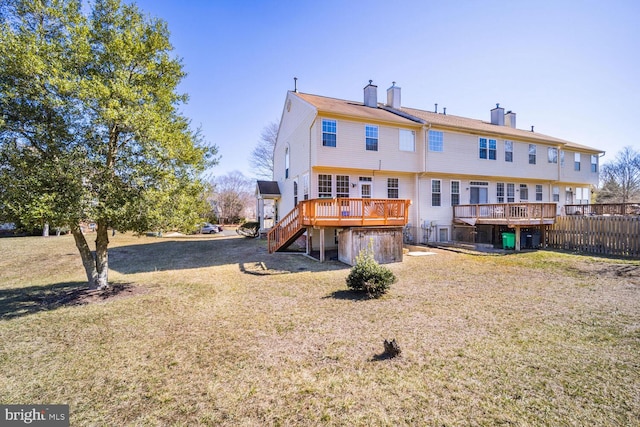 rear view of property with a lawn, a chimney, stairs, fence, and a wooden deck