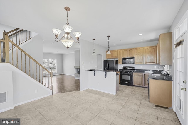 kitchen with dark countertops, a breakfast bar, open floor plan, black appliances, and a sink