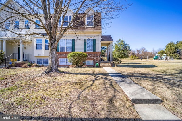 view of front of property with playground community, brick siding, and a front yard