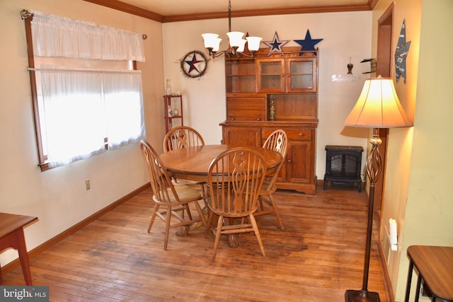 dining room featuring baseboards, hardwood / wood-style flooring, a wood stove, crown molding, and a chandelier