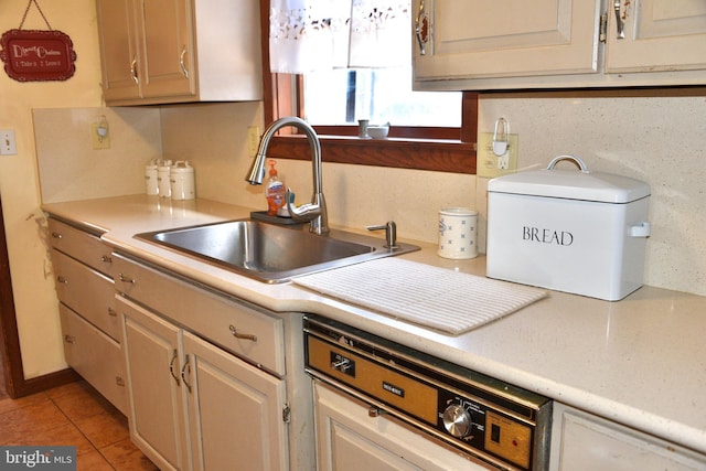 kitchen with light tile patterned floors, paneled dishwasher, light countertops, and a sink