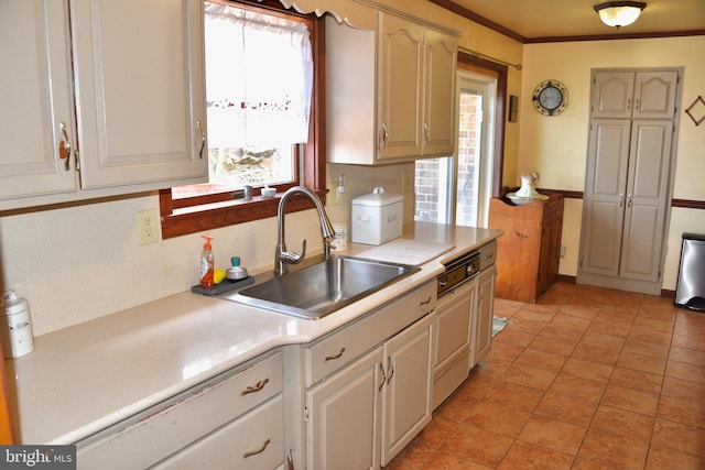 kitchen featuring decorative backsplash, paneled dishwasher, light countertops, crown molding, and a sink