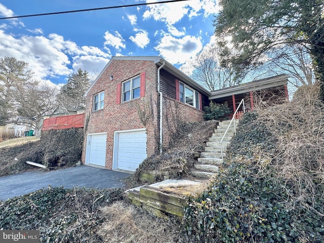 view of home's exterior with a garage, aphalt driveway, stairway, and brick siding