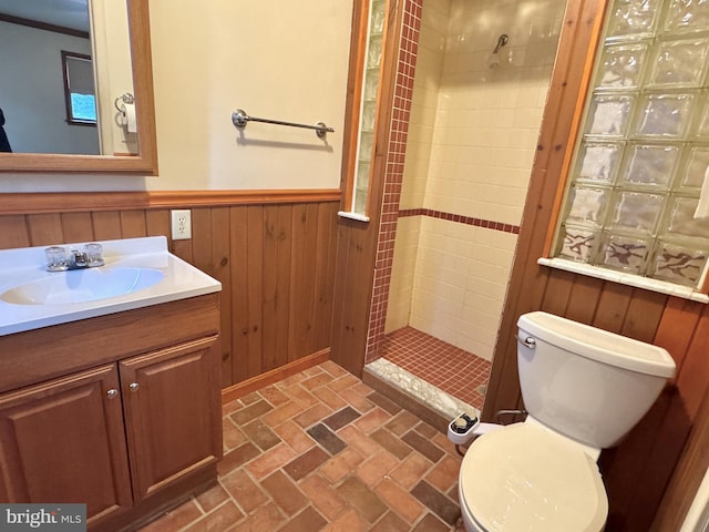 bathroom with toilet, a shower stall, vanity, and wainscoting