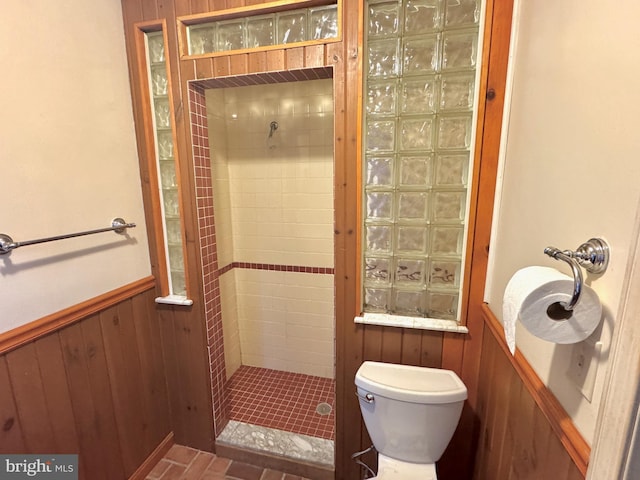 full bath featuring toilet, a wainscoted wall, a shower stall, and wooden walls