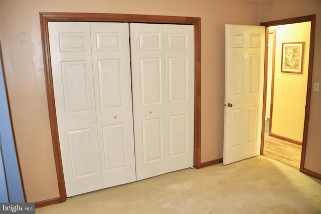 unfurnished bedroom with light carpet, a closet, and baseboards