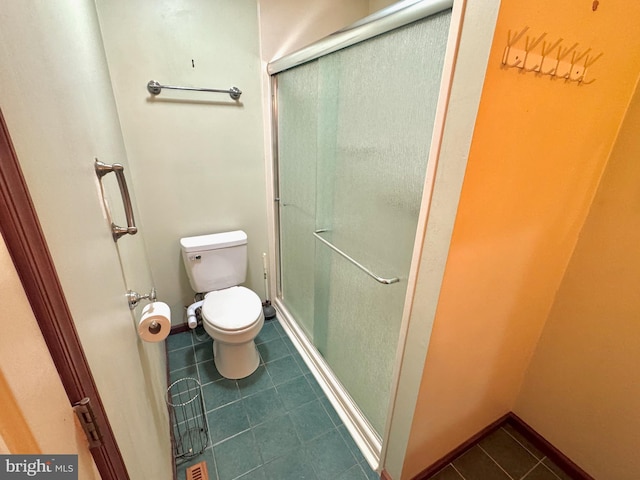 bathroom featuring a stall shower, baseboards, toilet, and tile patterned floors