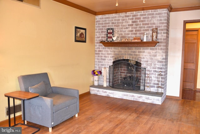 sitting room featuring a brick fireplace, visible vents, ornamental molding, and hardwood / wood-style floors