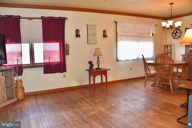 dining space featuring baseboards, a notable chandelier, crown molding, and hardwood / wood-style floors