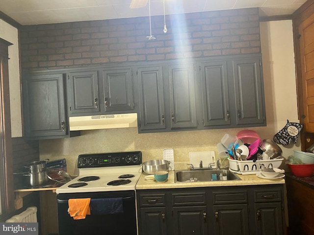 kitchen with under cabinet range hood, light countertops, a sink, and range with electric stovetop