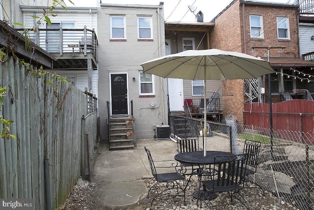 rear view of property featuring entry steps, a fenced backyard, a balcony, and central air condition unit