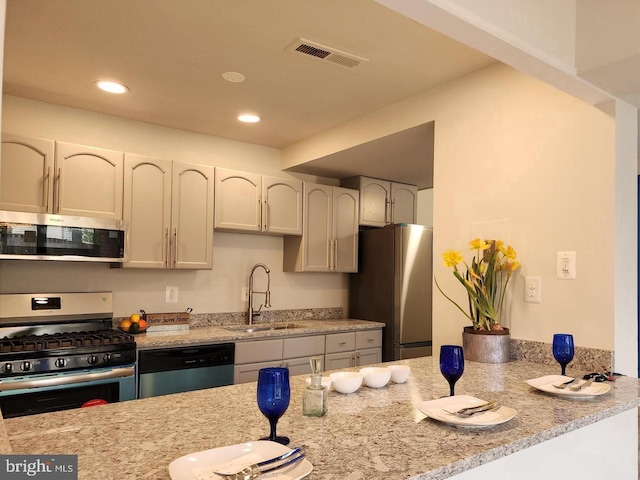 kitchen featuring light stone counters, recessed lighting, a sink, visible vents, and appliances with stainless steel finishes