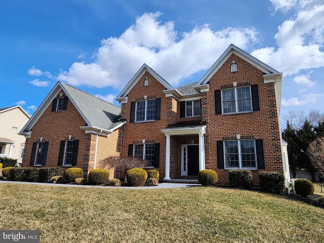 traditional home featuring brick siding, roof with shingles, and a front lawn