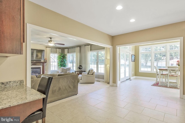 living room featuring baseboards, ceiling fan, light tile patterned floors, recessed lighting, and a glass covered fireplace