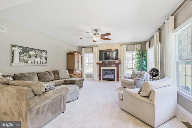 living area with visible vents, light colored carpet, a healthy amount of sunlight, and ceiling fan