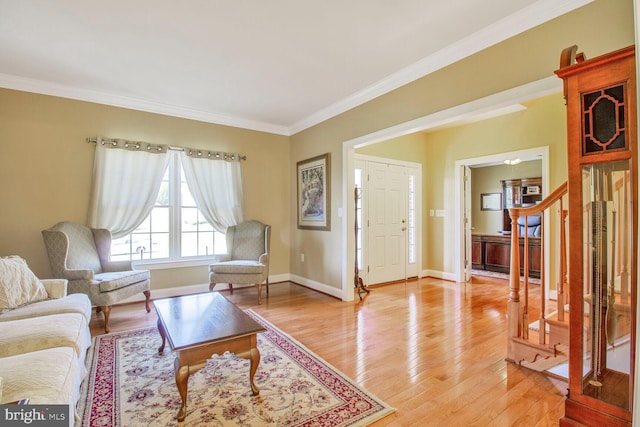 living area with stairs, crown molding, baseboards, and light wood-type flooring