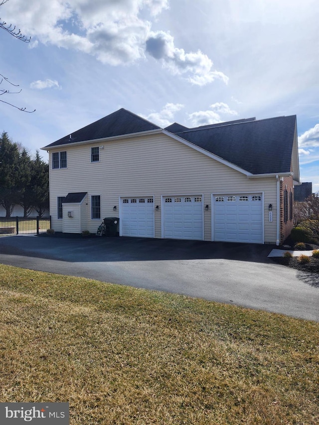 view of side of property featuring aphalt driveway, a garage, and fence