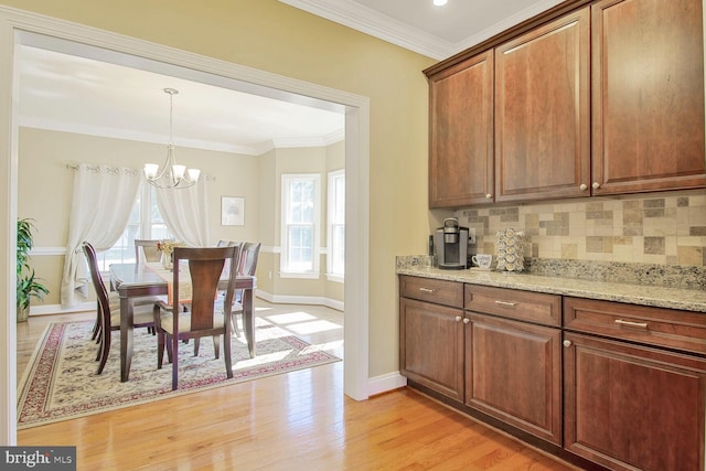 kitchen with crown molding, light wood-type flooring, backsplash, and a chandelier