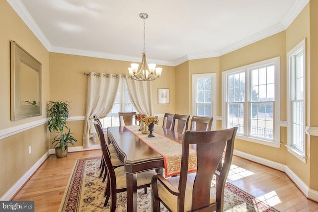 dining space with light wood-type flooring, baseboards, a chandelier, and ornamental molding