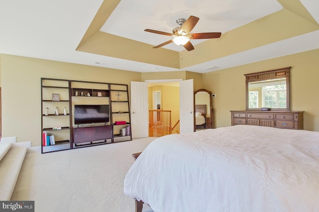 carpeted bedroom featuring visible vents, a raised ceiling, and ceiling fan