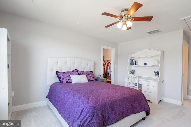 bedroom with visible vents, baseboards, light colored carpet, and a spacious closet