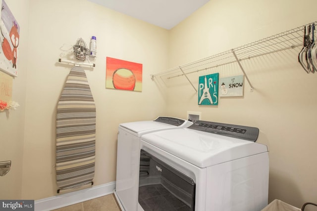 laundry area with washing machine and clothes dryer, laundry area, tile patterned floors, and baseboards