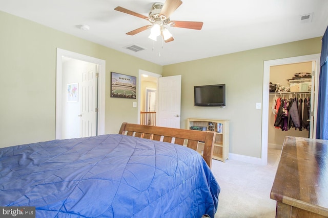 carpeted bedroom with visible vents, baseboards, a walk in closet, and a ceiling fan