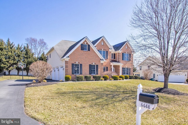 view of front facade with brick siding, a garage, driveway, and a front lawn