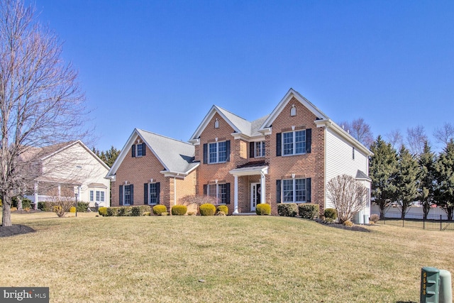 view of front of property with brick siding, a front lawn, and fence