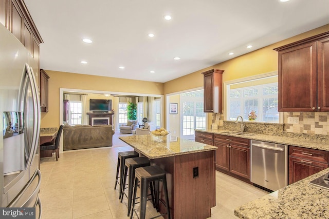 kitchen featuring a sink, a kitchen island, open floor plan, appliances with stainless steel finishes, and decorative backsplash