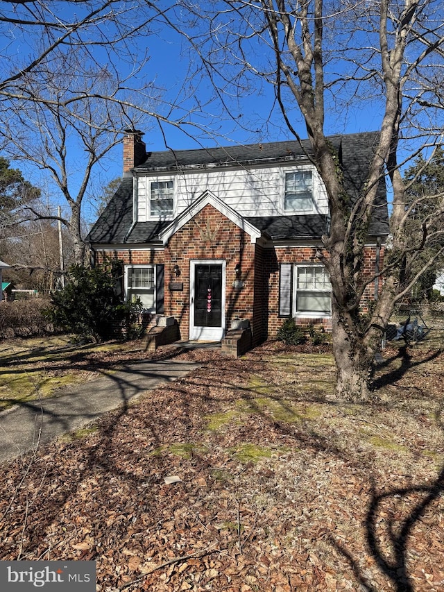 view of front of house featuring brick siding and a chimney