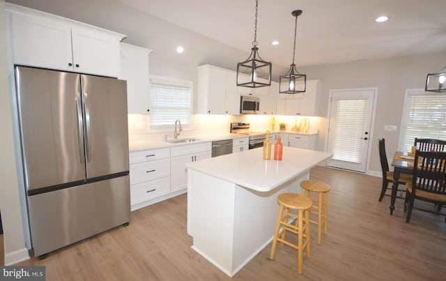 kitchen featuring appliances with stainless steel finishes, a center island, a kitchen bar, a sink, and recessed lighting