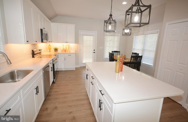 kitchen featuring stainless steel appliances, tasteful backsplash, light wood-style flooring, a kitchen island, and a sink