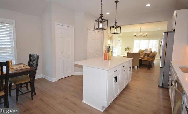 kitchen with light wood finished floors, appliances with stainless steel finishes, open floor plan, light countertops, and recessed lighting