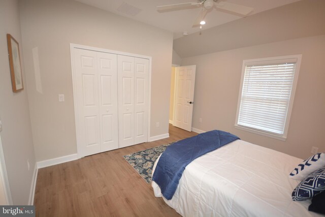 bedroom with lofted ceiling, ceiling fan, wood finished floors, baseboards, and a closet