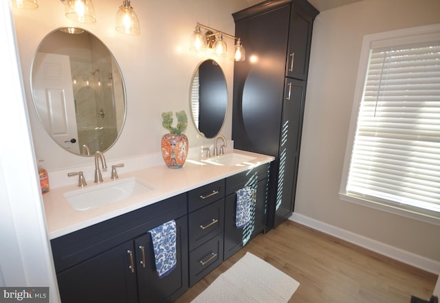 full bathroom featuring baseboards, walk in shower, a sink, and wood finished floors