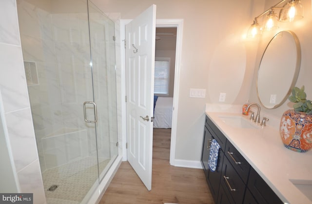 full bath with double vanity, connected bathroom, a sink, a shower stall, and wood finished floors