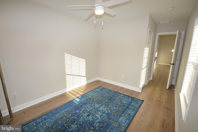 unfurnished room featuring ceiling fan, wood finished floors, visible vents, and baseboards