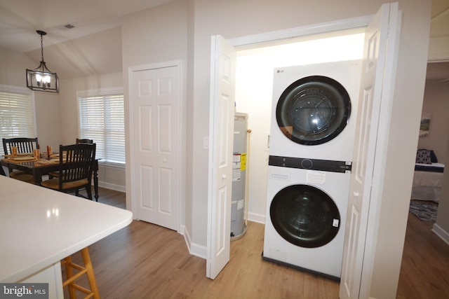 laundry room with stacked washer and dryer, laundry area, visible vents, baseboards, and light wood-style floors