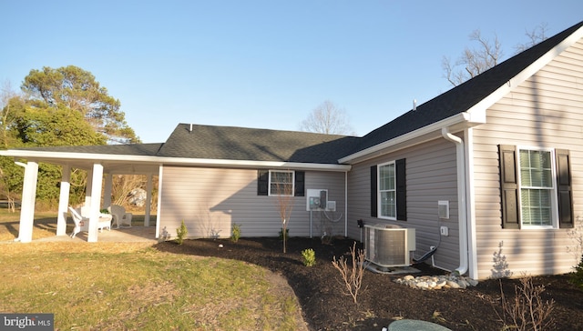 rear view of house featuring central air condition unit, a yard, roof with shingles, and a patio