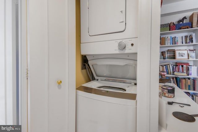 clothes washing area featuring stacked washer and dryer and laundry area