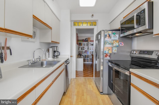 kitchen with light wood finished floors, light countertops, appliances with stainless steel finishes, and a sink