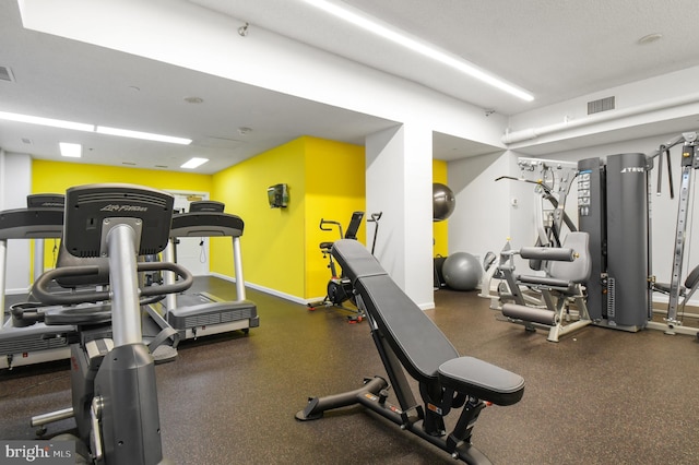 exercise room with baseboards and visible vents