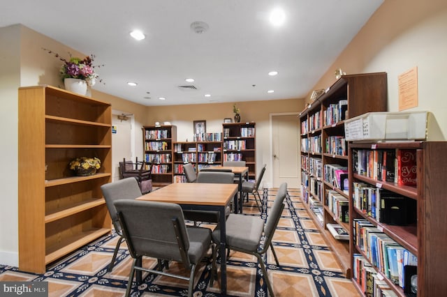 office space featuring wall of books, visible vents, and recessed lighting